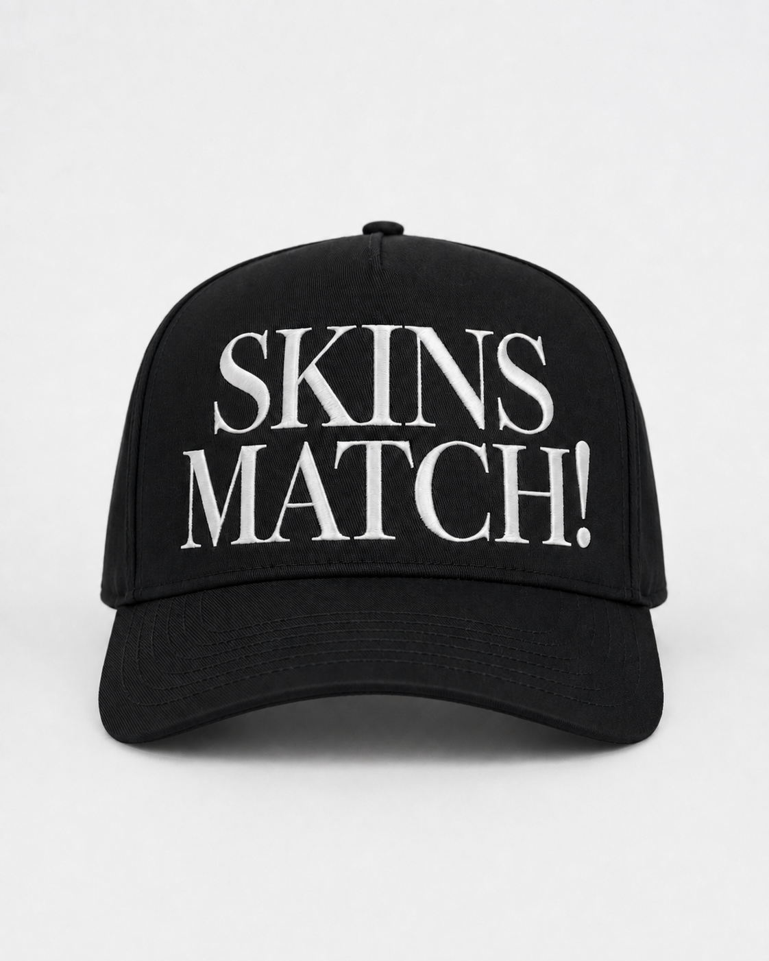 Black 5-panel snapback cap with white raised “SKINS MATCH!” embroidery on the front crown