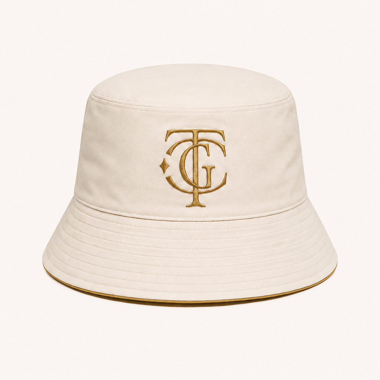 An off-white bucket hat featuring an embroidered gold monogram logo on the front, set against a solid off-white background.