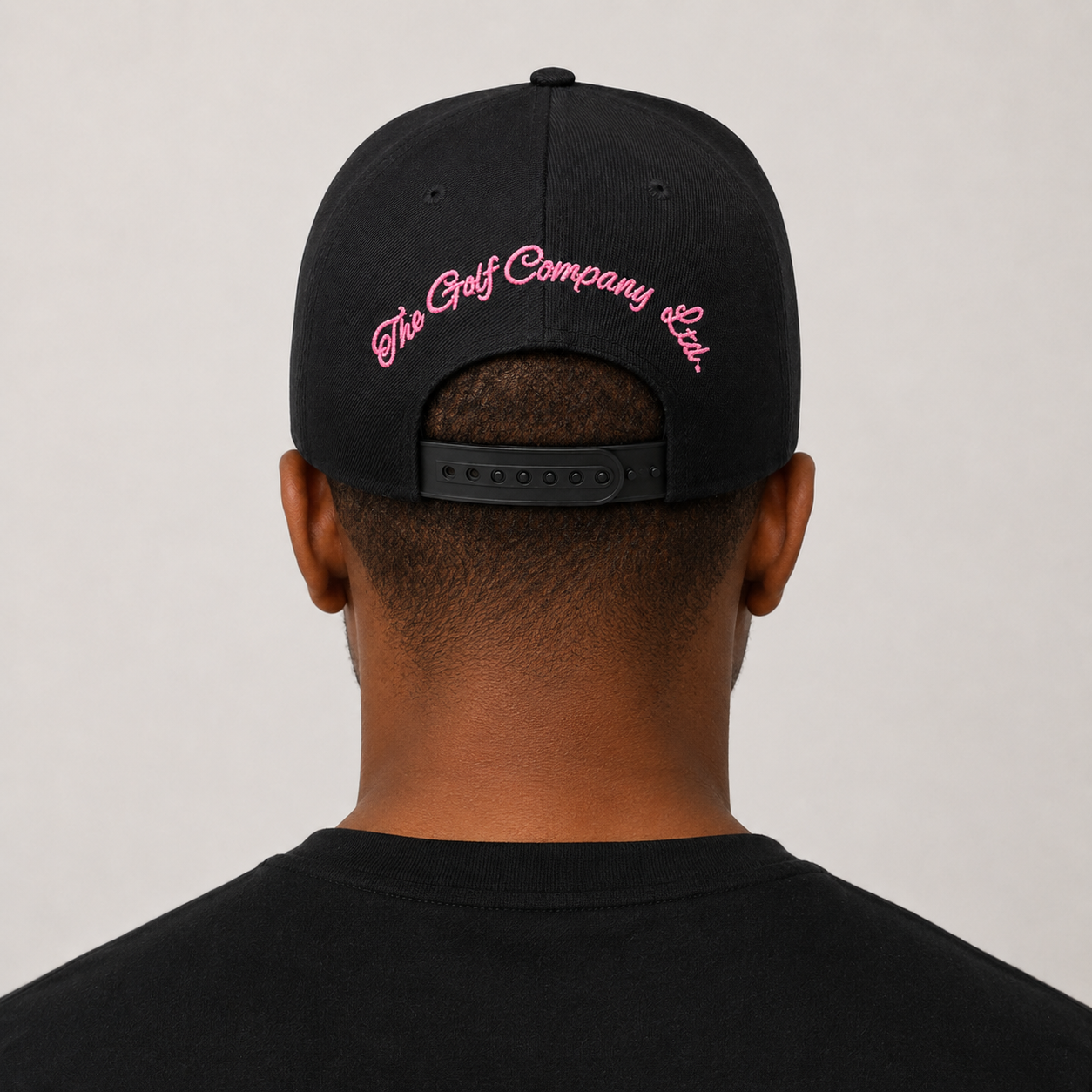 Person wearing a black cap with pink text on a plain background