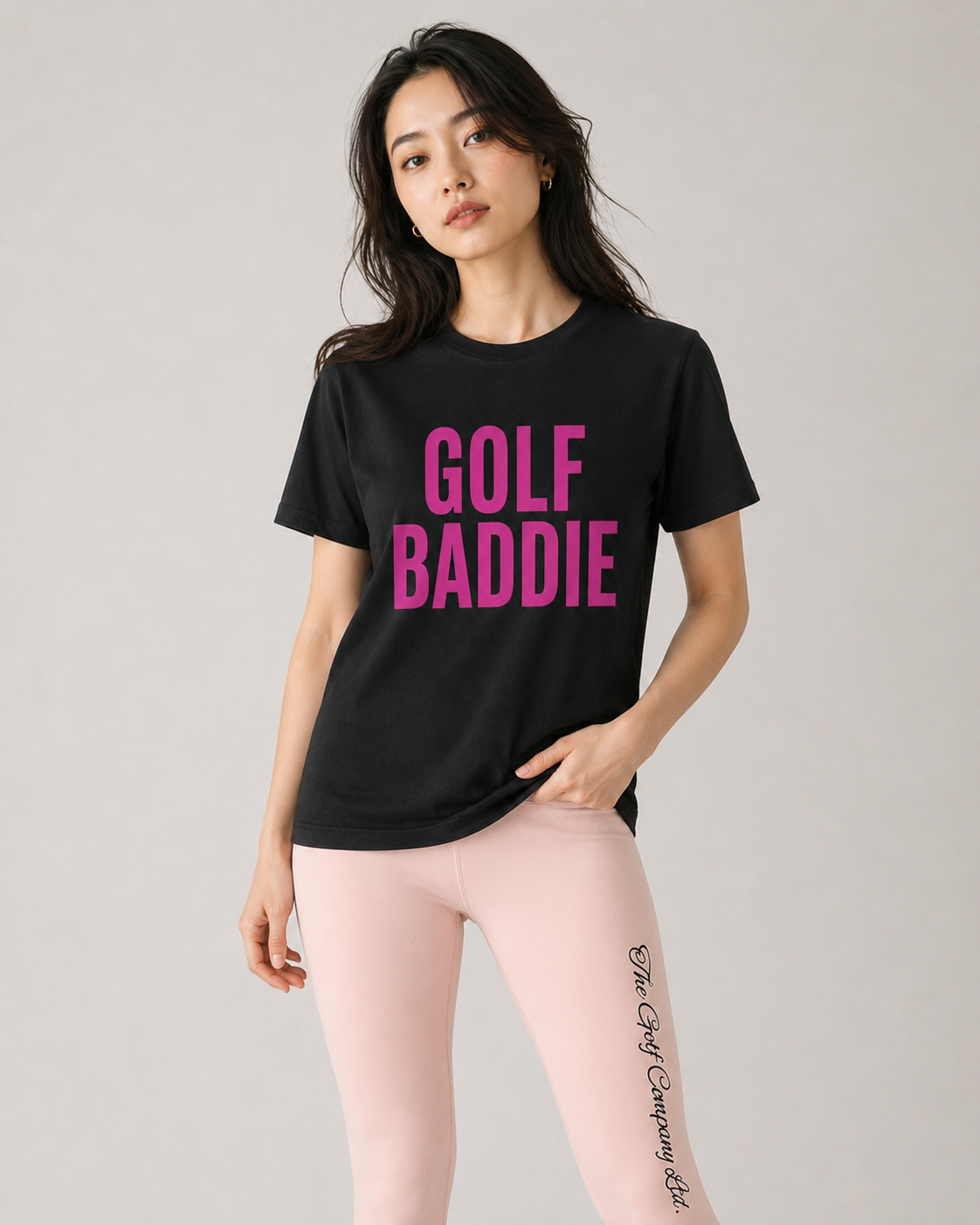 Woman wearing a black t-shirt with 'GOLF BADDIE' in pink text on a plain background