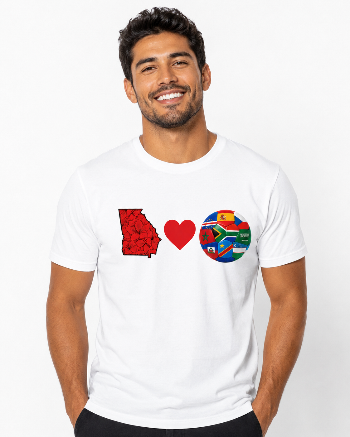 Male model wearing a white Georgia Loves Fútbol tee with Georgia state, heart, and multi-nation soccer ball chest graphic.