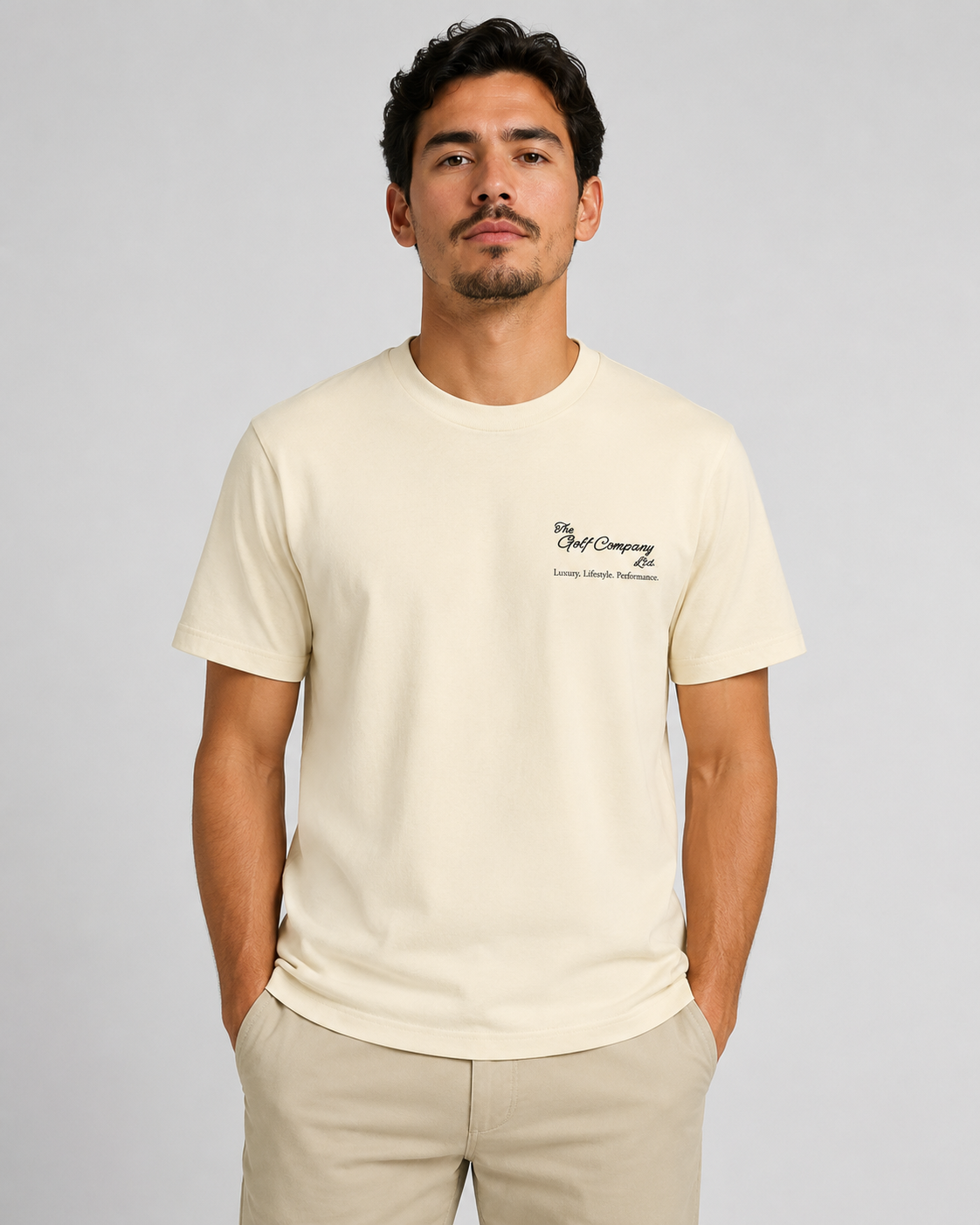 Man wearing a beige t-shirt with a logo on a gray background