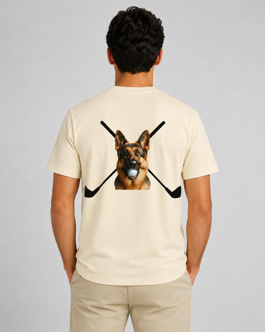 Person wearing a beige t-shirt with a graphic of a German Shepherd dog and crossed hockey sticks on the back.