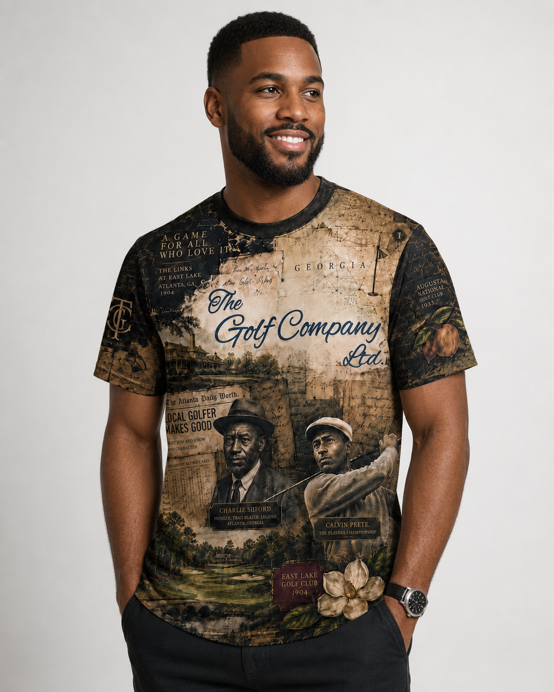A man wearing a short-sleeve graphic t-shirt with a vintage golf-themed print, featuring text like 'The Golf Company Ltd.' and illustrations of golfers, set against a plain light gray background.