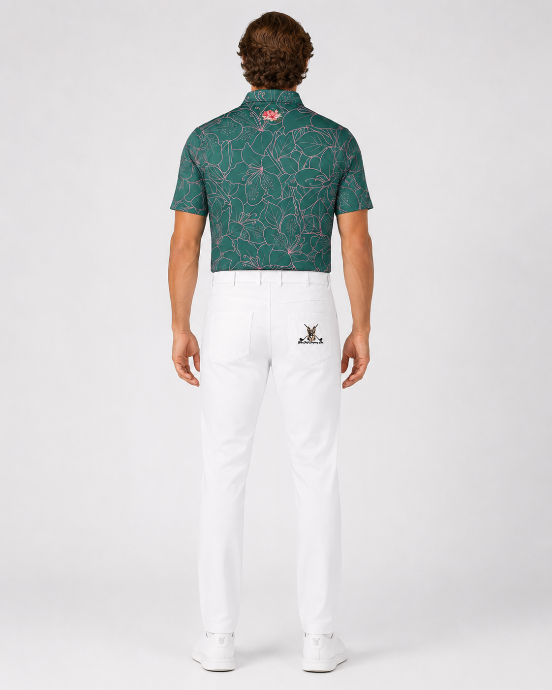 Man wearing a green patterned polo shirt and white pants on a white background