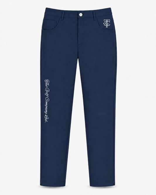 A pair of navy blue slim-fit jeans with white embroidered details, including a 'TGC' monogram on the right pocket and 'The Golf Company, Ltd.' script on the left leg, shown against a plain white background.