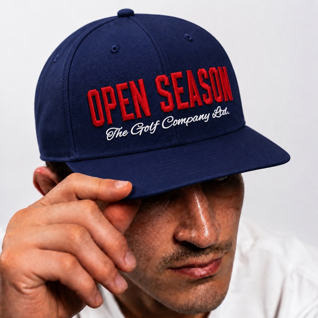 Navy blue cap with 'Open Season' text worn by a person on a white background