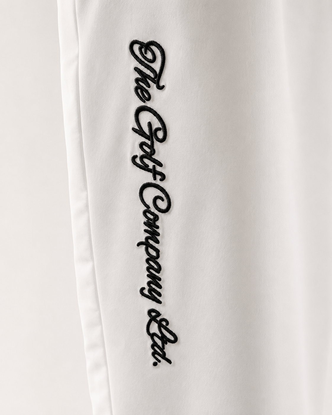 White pants with black embroidered text on a white background