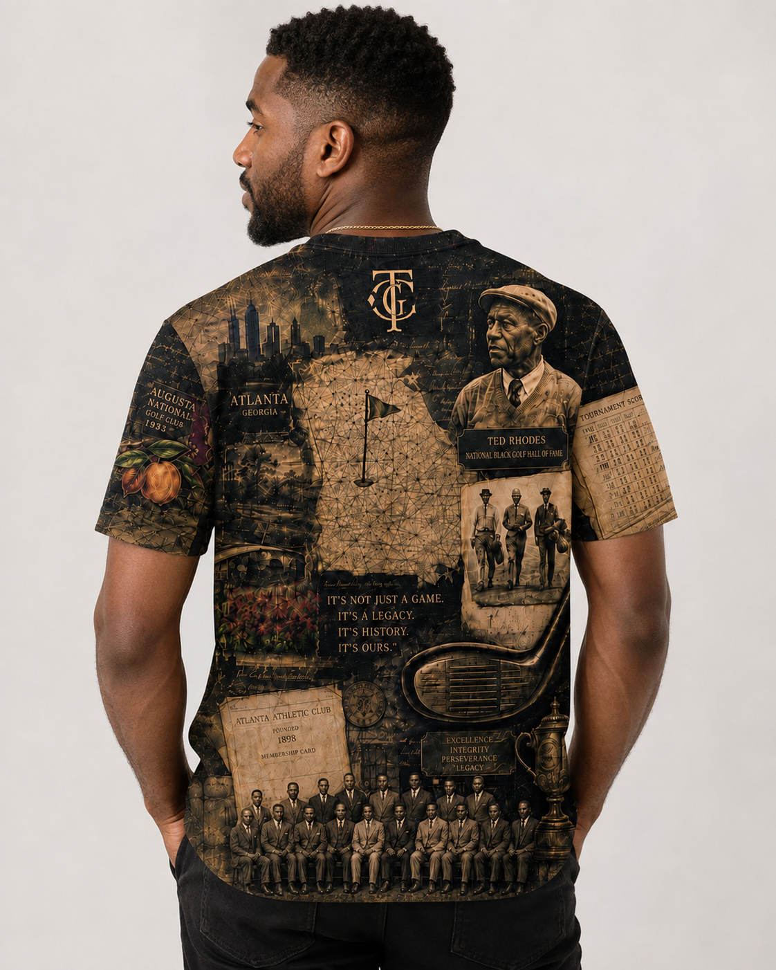 A man wearing a black short-sleeve t-shirt with a detailed sepia-toned graphic print on the back, featuring historical sports imagery, text, and a team logo, shown from a rear three-quarter view against a light gray studio background.