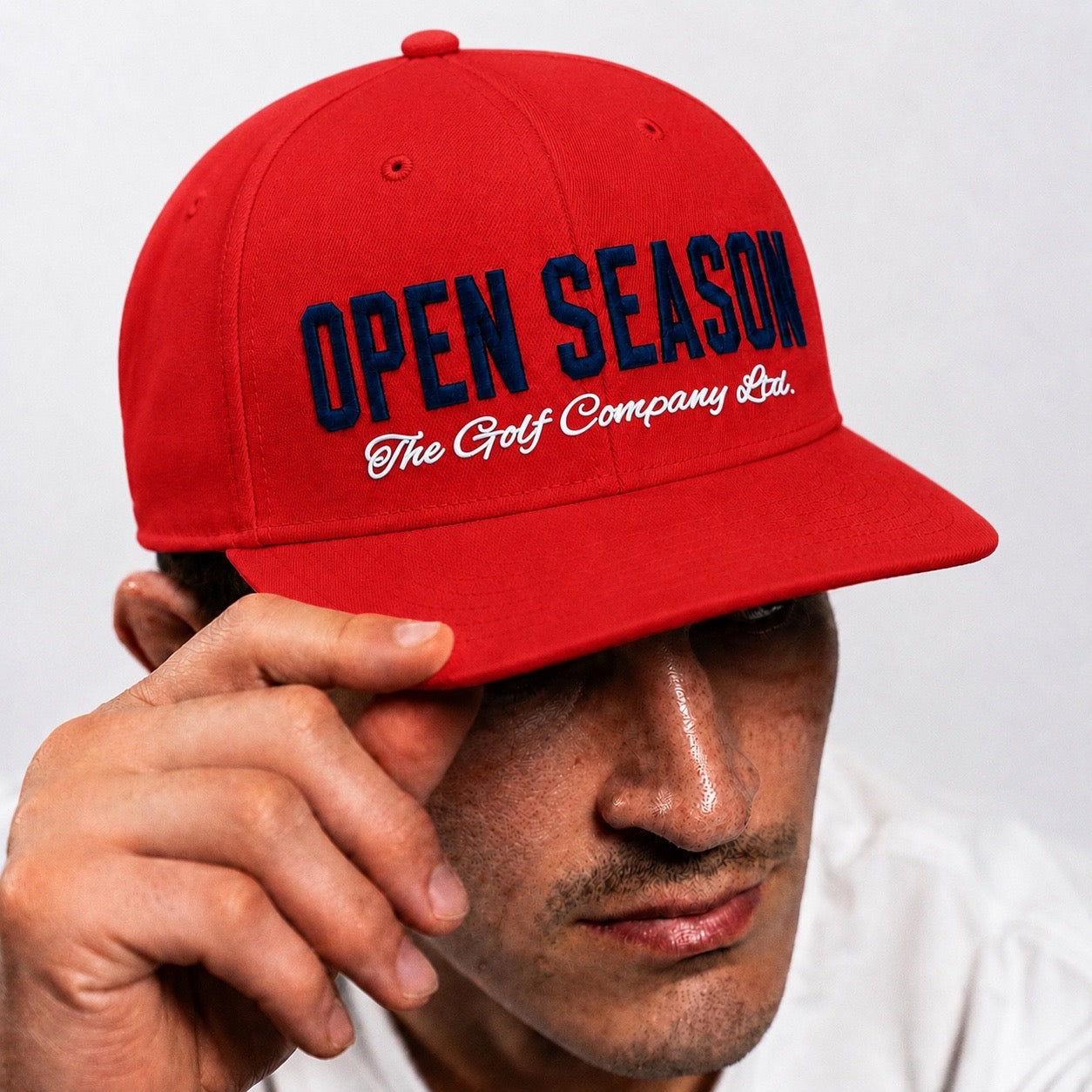 Red cap with 'Open Season' text held by a person against a white background