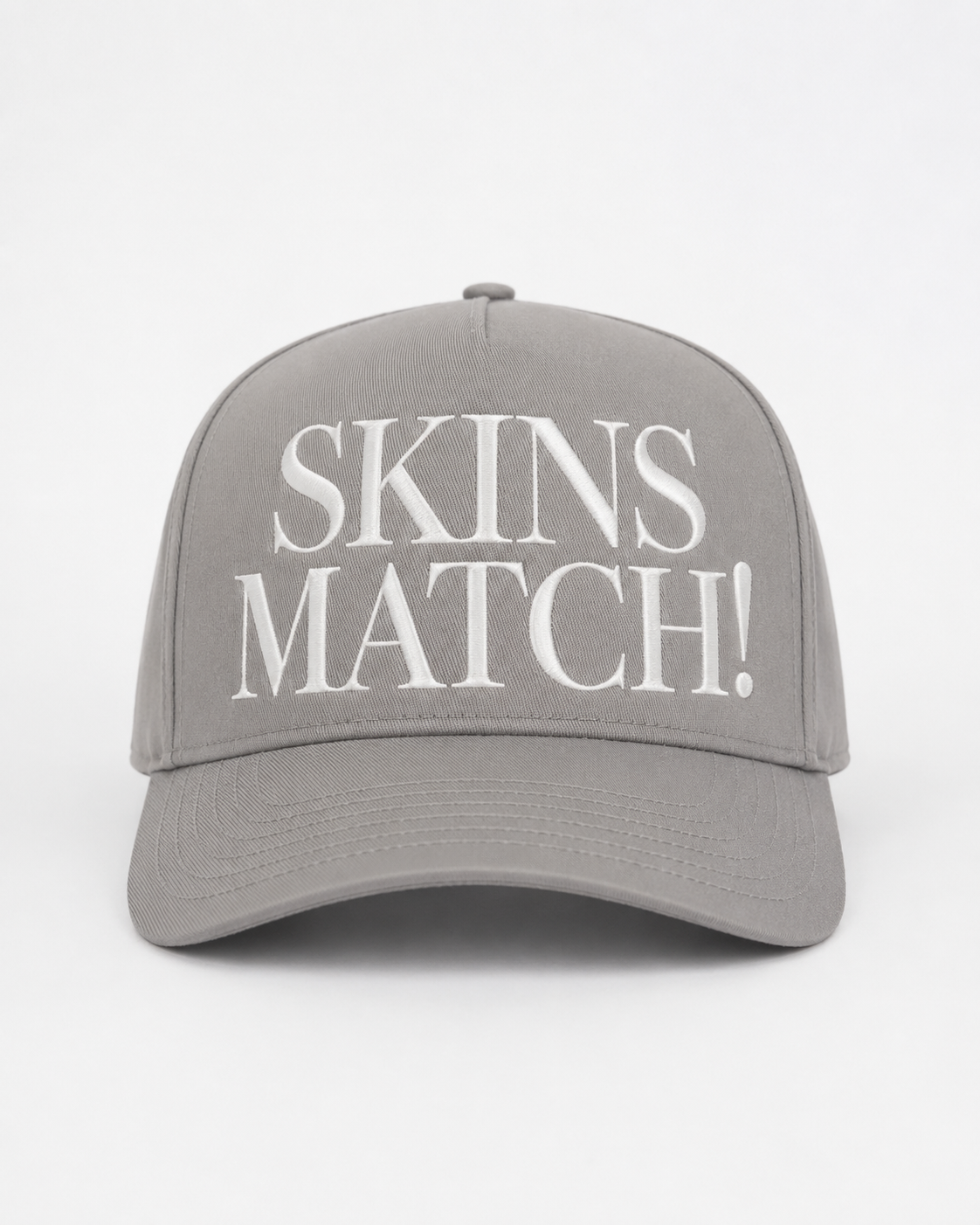 Grey 5-panel snapback cap with white raised “SKINS MATCH!” embroidery on the front crown