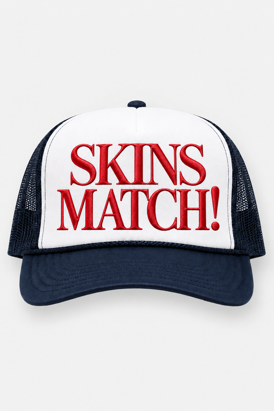 Front product view of the SKINS MATCH! USA Navy Trucker Hat featuring a white front panel, navy brim and mesh, and bold red embroidered SKINS MATCH! lettering.