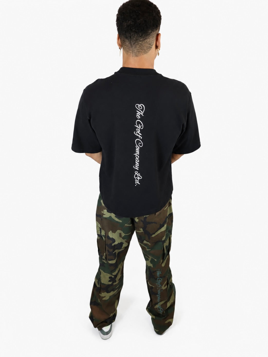 Male model wearing a black oversized Signature Hudson tee with vertical The Golf Company Ltd. script logo on the back.