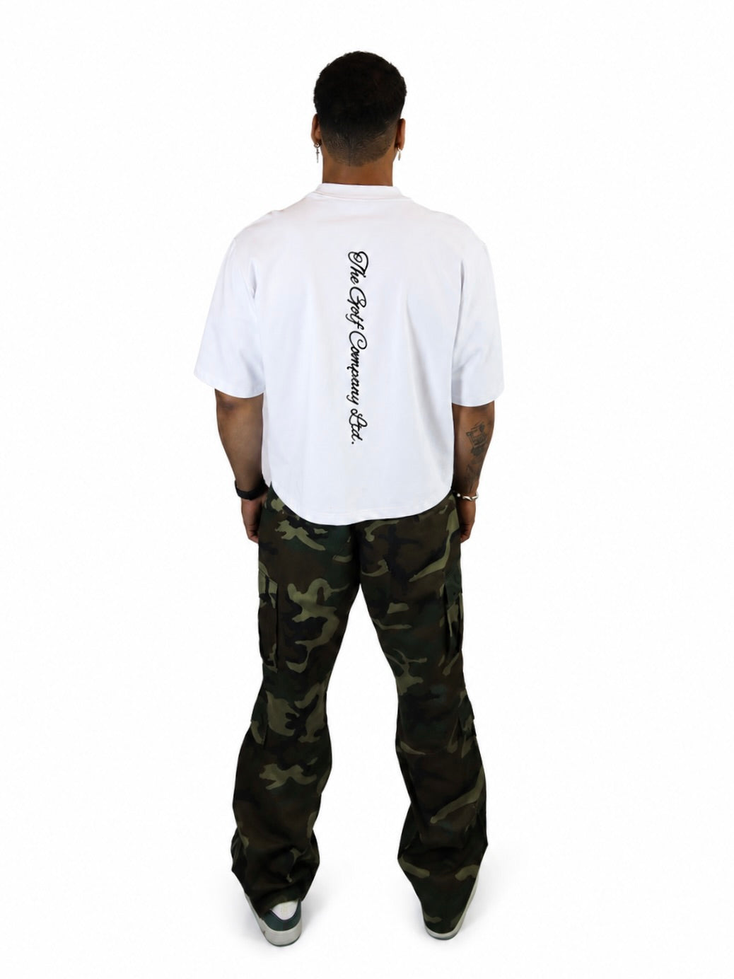 Male model wearing a white oversized Signature Hudson tee with vertical The Golf Company Ltd. script logo on the back.