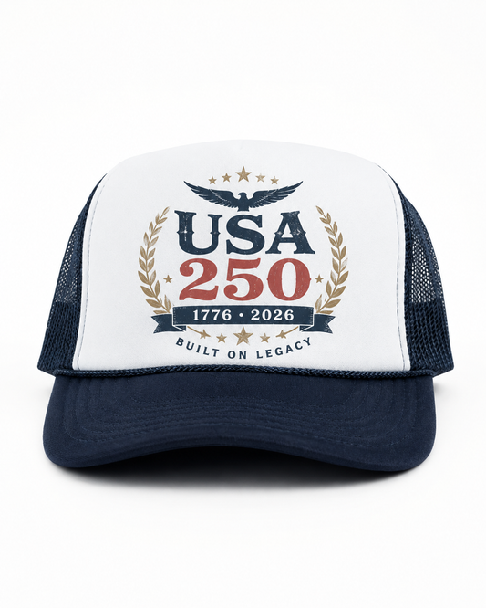 Navy and white USA 250 trucker cap with eagle crest, gold laurel artwork, red 250 lettering, and Built On Legacy text.