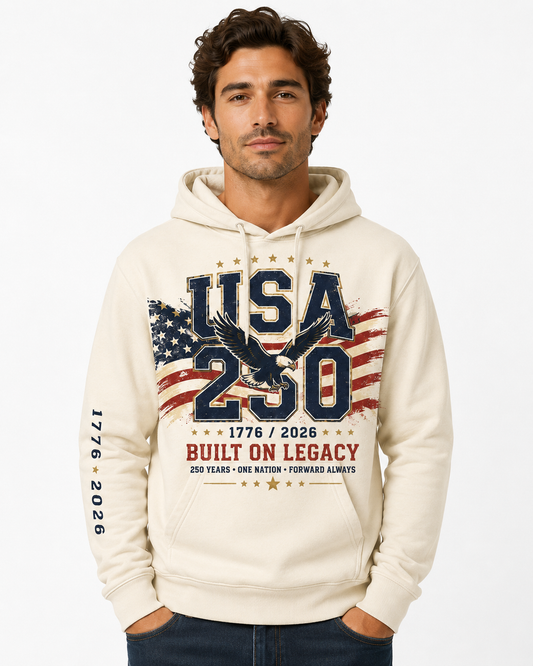 Male model wearing a vintage cream USA 250 fleece hoodie with a large patriotic eagle, American flag, 1776–2026, and “Built On Legacy” front graphic.