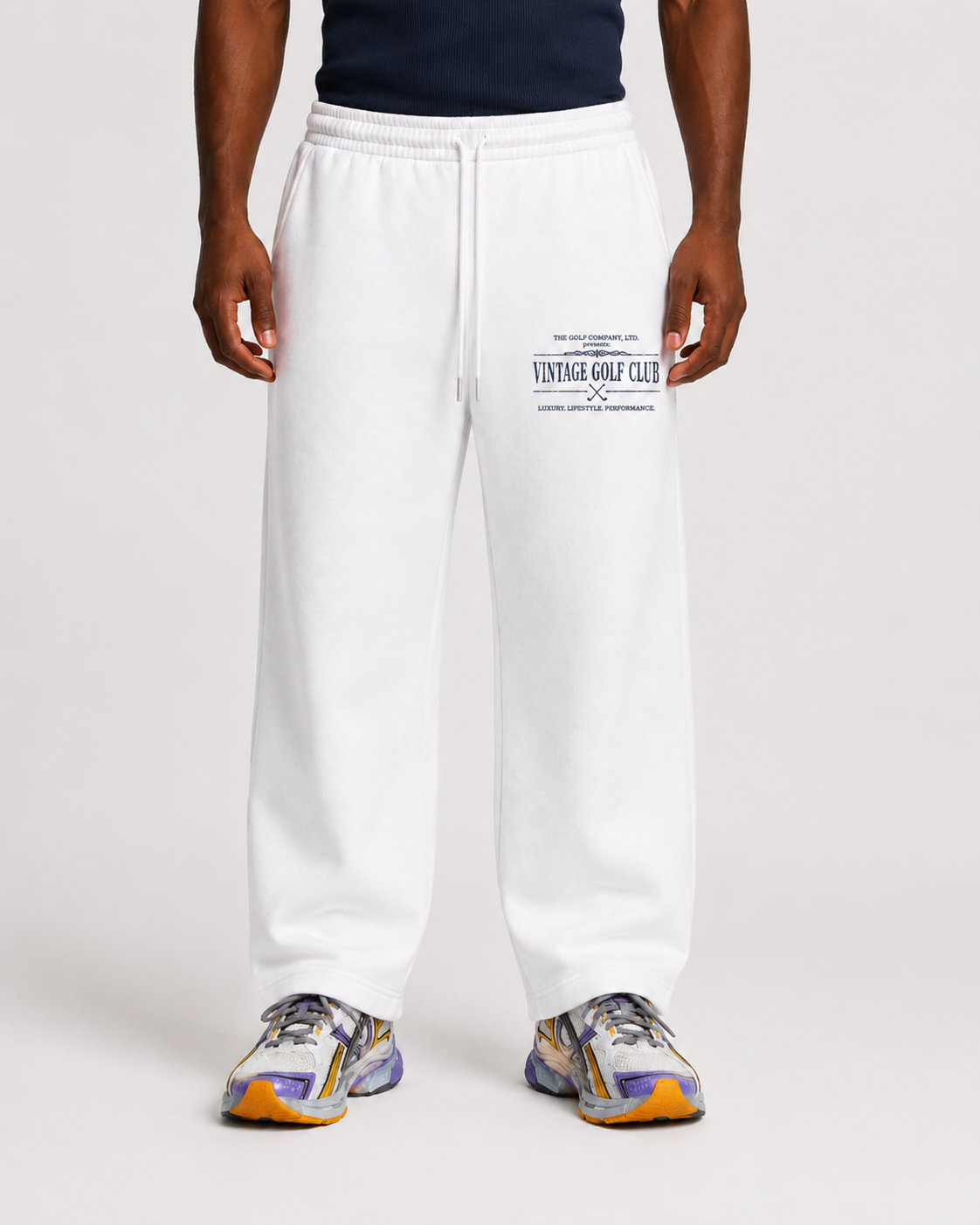White Vintage Golf Club weathered sweatpants on male model with navy tank top and athletic sneakers.
