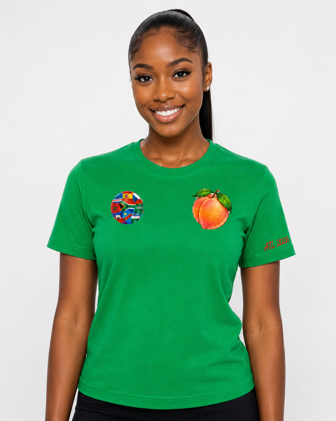 Female model wearing a Kelly green Atlanta 2026 Peach Crest tee with multi-nation soccer ball, Georgia peach chest graphic, and ATL 2026 sleeve detail.
