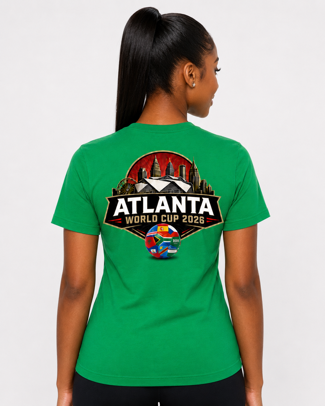 Female model wearing a Kelly green Atlanta 2026 Peach Crest tee with large Atlanta skyline and stadium back graphic.